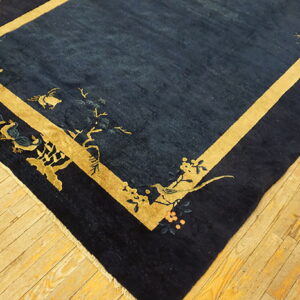 Navy blue rug featuring a golden yellow border and decorative patterns of birds and flowers on wood plank flooring.