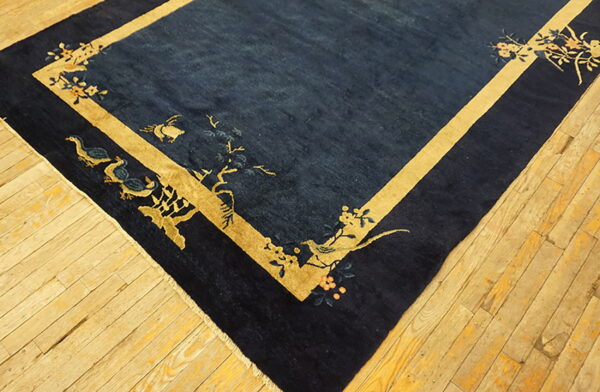 Navy blue rug featuring a golden yellow border and decorative patterns of birds and flowers on wood plank flooring.