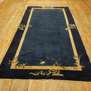 Navy blue rectangular rug with beige borders and bird motifs lies on distressed golden wood planks.