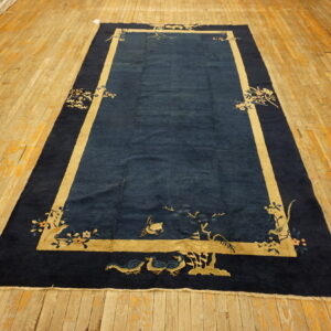 Plush navy blue rug featuring tan borders and corner botanical designs on wide wooden planks.