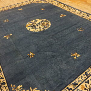 Dark blue rug with gold and cream floral patterns lies on a light wooden plank floor.
