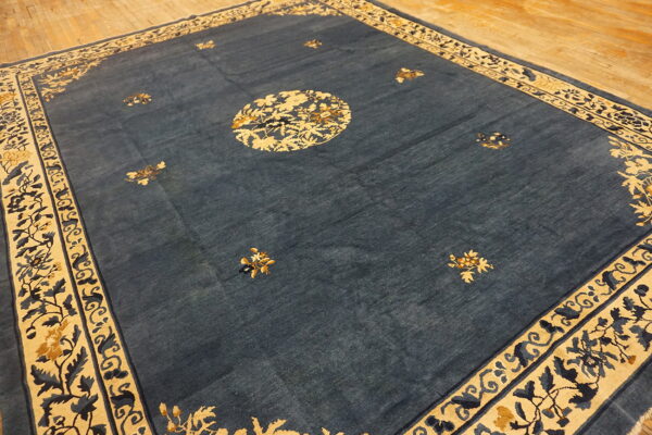 Dark blue rug with gold and cream floral patterns lies on a light wooden plank floor.