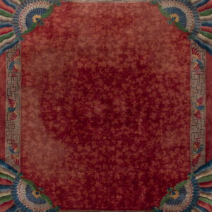 Burgundy rug with faint floral pattern, framed by multicolored borders featuring ornate fan and bird designs.