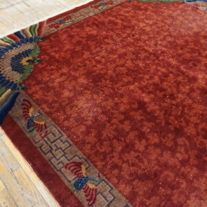 Red faded rug with a tonal field and a vibrant corner border featuring blue, green, and red fan designs.