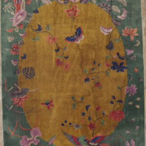 Green rug featuring a golden central oval medallion framed by colorful flowers, a bird, and a butterfly.
