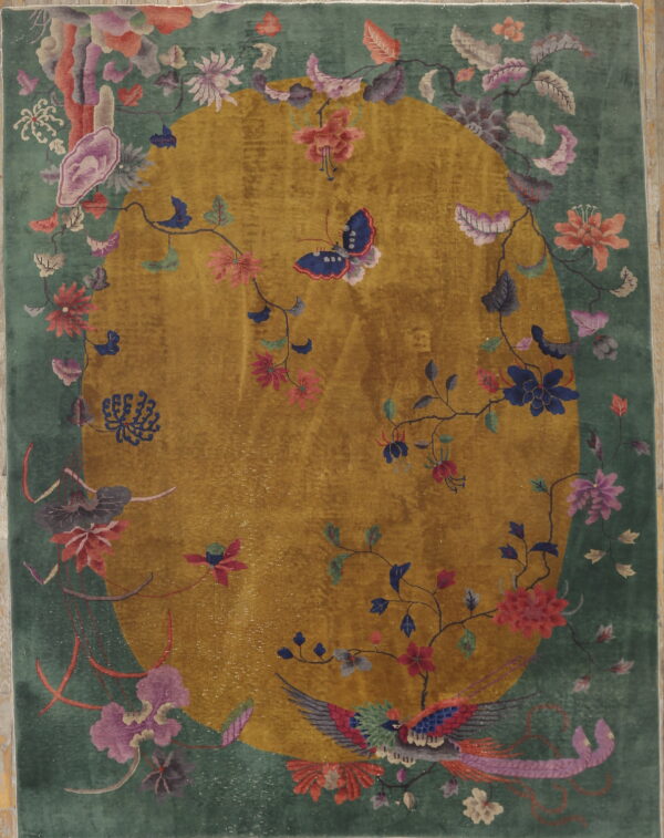 Green rug featuring a golden central oval medallion framed by colorful flowers, a bird, and a butterfly.