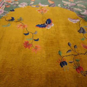 Gold and moss green rug detailed with colorful vines, large floral sprays, and a prominent blue butterfly motif.