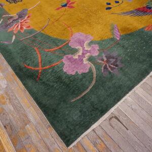 Plush yellow and emerald rug with floral patterns rests on distressed wooden plank flooring.