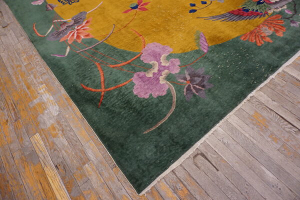 Plush yellow and emerald rug with floral patterns rests on distressed wooden plank flooring.