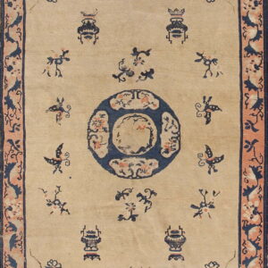 Tan rug featuring a navy blue center medallion, stylized vases, and scattered birds within a peach border.