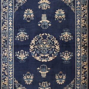 Ornate dark blue rug with beige and teal motifs, featuring multiple borders and a central floral wreath.
