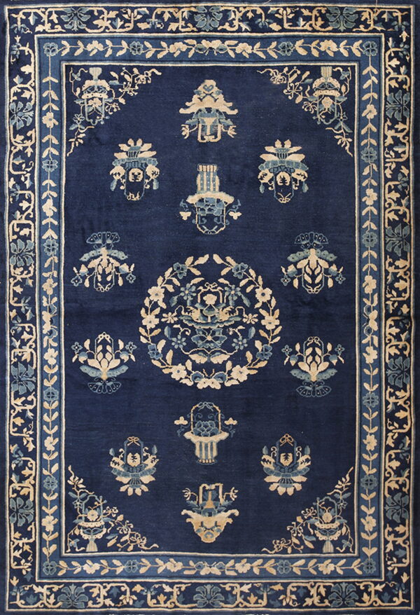 Ornate dark blue rug with beige and teal motifs, featuring multiple borders and a central floral wreath.