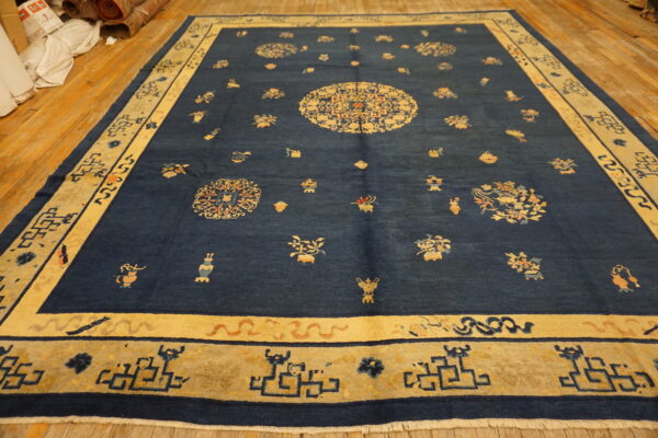 Large navy blue rug featuring a central gold medallion and scattered traditional motifs on wood planks.