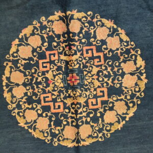 Dark blue rug with a centralized gold and peach medallion featuring geometric fretwork and floral designs.