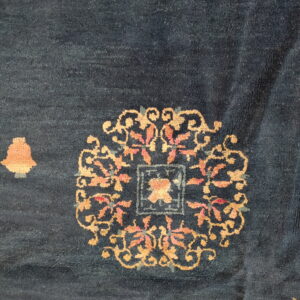 Dark blue low-pile rug detail showing ornate gold and coral floral medallions and scattered motifs.