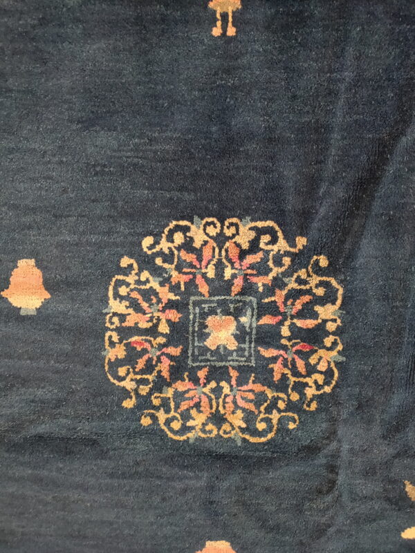 Dark blue low-pile rug detail showing ornate gold and coral floral medallions and scattered motifs.