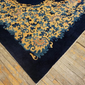 A dark blue border and gold scrolling floral rug corner rests on aged, light brown wooden floorboards.