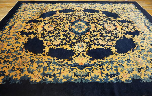 A navy and gold oriental-style rug with intricate floral motifs rests on light wood planks.