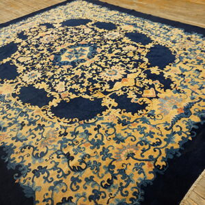 Navy blue rug with a dense gold floral pattern, prominent cartouches, lying on weathered wood planking.