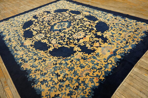 Navy blue rug with a dense gold floral pattern, prominent cartouches, lying on weathered wood planking.