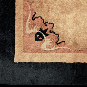 The rug border features a wide black edge surrounding a pink and beige stylized floral corner design.