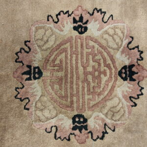 Beige rug featuring a large medallion with symbolic patterns in pinkish-tan and black.