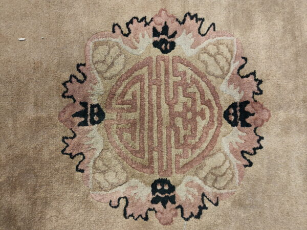 Beige rug featuring a large medallion with symbolic patterns in pinkish-tan and black.