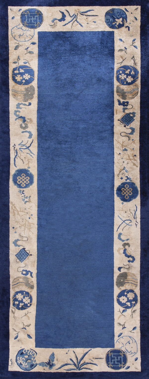 Blue runner rug featuring a wide beige border decorated with blue and tan symbolic medallions and plant motifs.