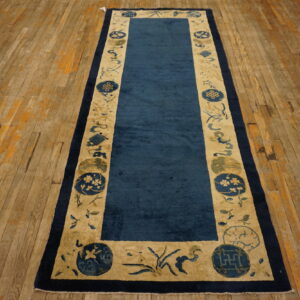 Dark blue runner rug with a wide tan border and blue symbolic motifs rests on distressed plank floor.