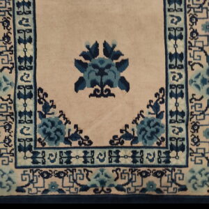 Cream rug with a stylized blue floral medallion and traditional blue geometric and floral borders.