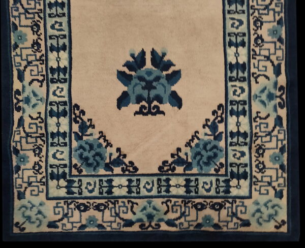 Cream rug with a stylized blue floral medallion and traditional blue geometric and floral borders.