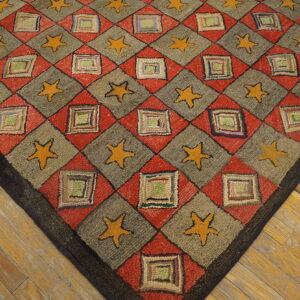 Textured rug displaying a red, gray, and yellow diamond and star pattern on distressed wooden floorboards.