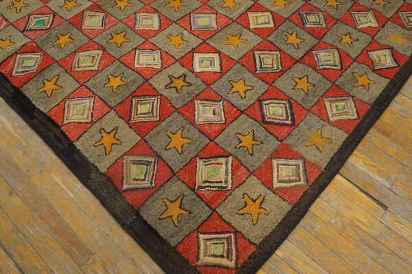 Textured rug displaying a red, gray, and yellow diamond and star pattern on distressed wooden floorboards.