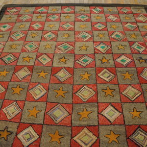 Checkerboard rug with alternating red diamond squares and gray star squares on distressed wood flooring.