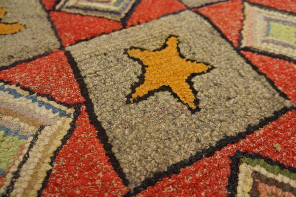 Textured rug detail shows a yellow star on a gray square, bordered by speckled red and multicolored stripes.