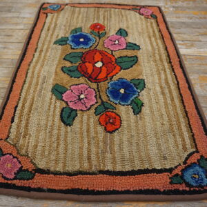 A textured rug with a central floral pattern on a tan striped field and a coral-colored border.