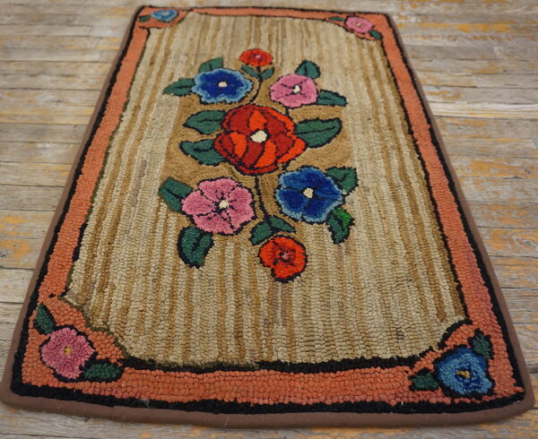 A textured rug with a central floral pattern on a tan striped field and a coral-colored border.