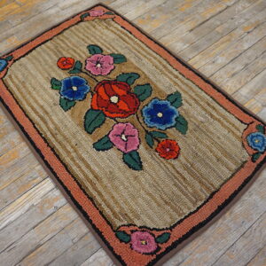 A thick, textured rug with colorful floral motifs and a coral border rests on worn gray wood planks.