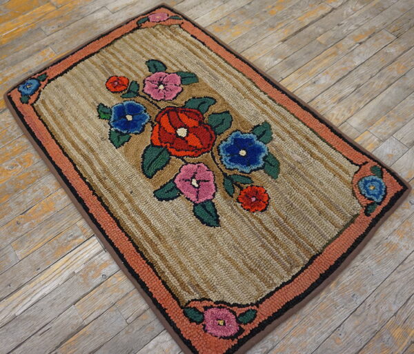 A thick, textured rug with colorful floral motifs and a coral border rests on worn gray wood planks.