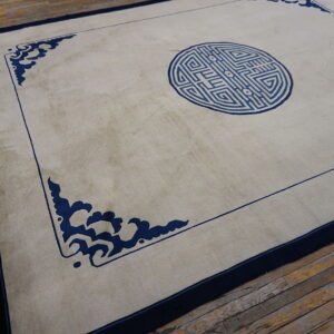 Light-colored rug with a blue central medallion and corner scrolls rests on rustic wood plank flooring.
