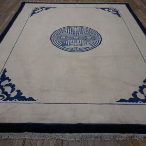 Light beige rug featuring a dark blue geometric medallion and stylized cloud spandrels on a rustic wood floor.