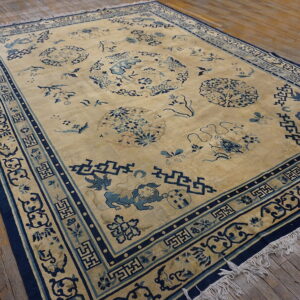 A large tan rug features detailed blue medallions and geometric borders on rustic wooden floorboards.
