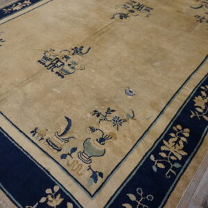 Gold rug featuring a wide navy blue border with gold floral patterns on worn wooden planks.