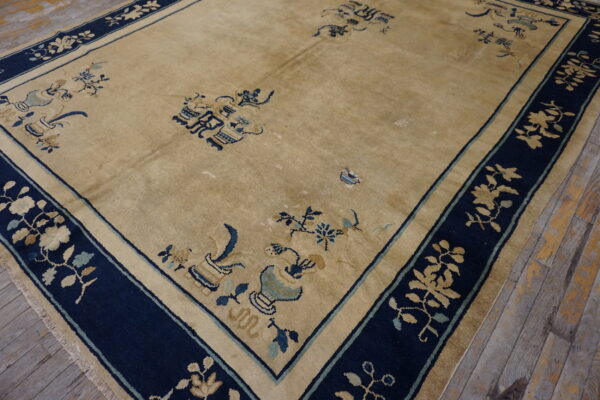 Gold rug featuring a wide navy blue border with gold floral patterns on worn wooden planks.