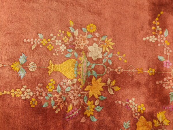 Rust low-pile rug with a detailed floral bouquet and vase pattern in bright yellow and pastel colors.