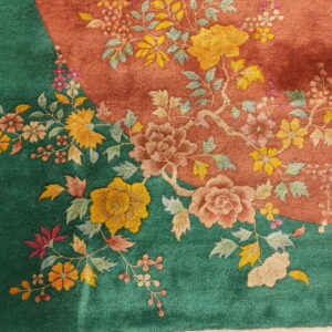 Detailed close-up of a rug featuring sculpted floral designs over contrasting deep green and terracotta fields.
