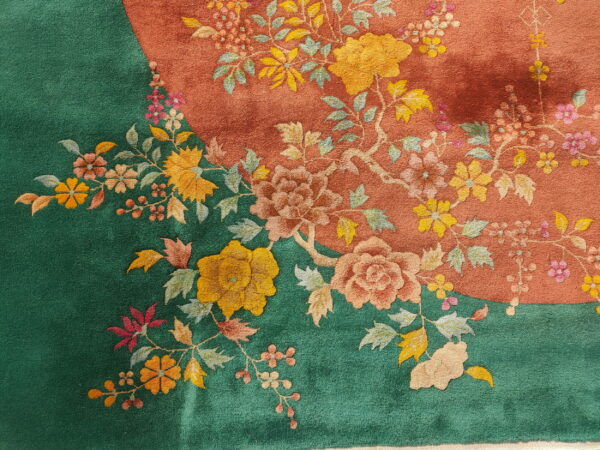Detailed close-up of a rug featuring sculpted floral designs over contrasting deep green and terracotta fields.