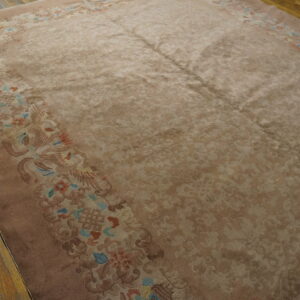 Taupe field rug with a detailed border in rose, blue, and coral on distressed wood flooring.