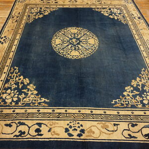 Dark blue rug featuring beige motifs, a central medallion, patterned borders, and light wood flooring.