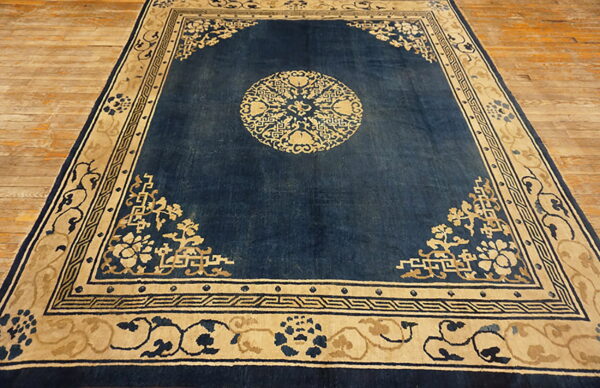 Dark blue rug featuring beige motifs, a central medallion, patterned borders, and light wood flooring.